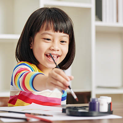 A happy Asian girl in kindergarten painting pictures.