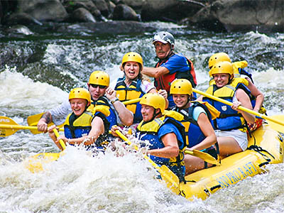 A group of kids white-water rafting, through river rapids, on summer camp.